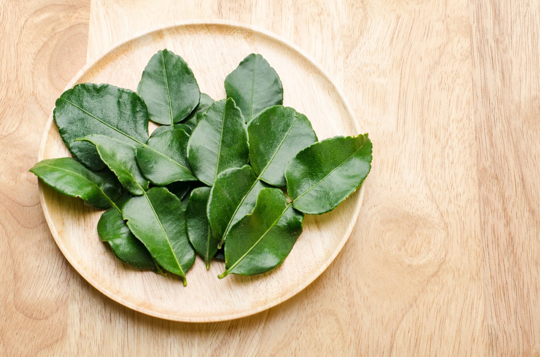 Kaffir Lime (flavorful leaves) on wooden background